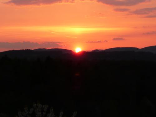 a sunset with the sun setting in the background at Gasthof-Hotel Lärmfeuer in Rohrbach