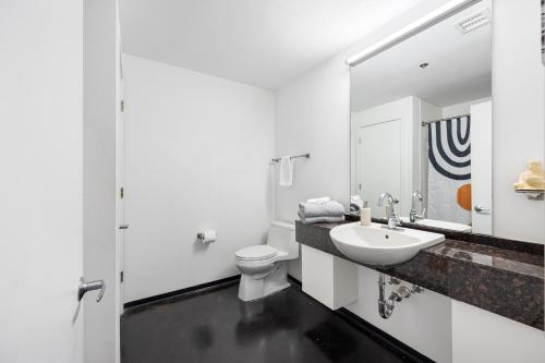 a white bathroom with a sink and a toilet at Streetcar Serenity Condo in New Orleans