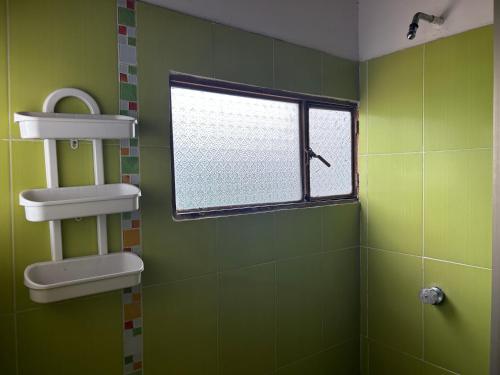 een groene badkamer met een raam en een wastafel bij Flor de Papel in Carmen de Apicalá