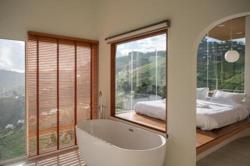 een badkamer met een bad, een bed en een raam bij nai r kaad in Chiang Mai