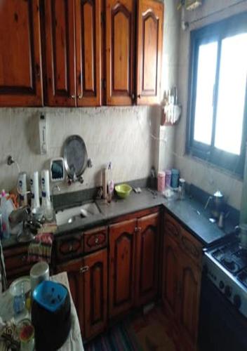 eine Küche mit Holzschränken, einem Waschbecken und einem Fenster in der Unterkunft Alexandria,Egypt in Alexandria