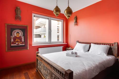 ein rotes Schlafzimmer mit einem Bett und einem Fenster in der Unterkunft Lasek Marceliński 2-Bedroom Apartment in Posen