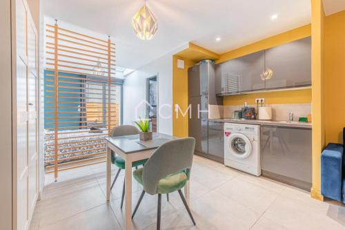 une cuisine avec une table et une machine à laver dans l'établissement Cosy lounge suit à 10 min de l'aéroport CDG TREMBLAY EN FRANCE, à Tremblay-en-France