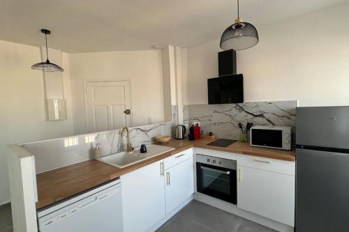 une cuisine avec des armoires blanches et un évier dans l'établissement Le Melo - Charmant appartement T2 neuf, à Perpignan