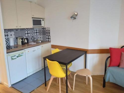une petite cuisine avec une table et deux chaises jaunes dans l'établissement 7mn walk to Metro, in ApartHotel, à Courbevoie