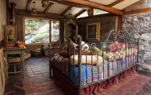 a bedroom with a iron bed in a stone wall at Hacienda Rumiloma in Quito
