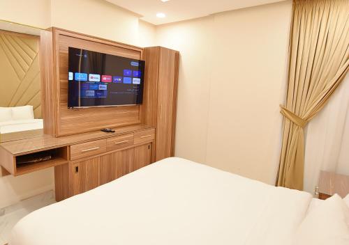 a bedroom with a bed and a flat screen tv at الدانة للشقق الفندقية in Kuwait