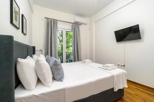 1 dormitorio con 1 cama blanca y TV en GK Embassy en Athens