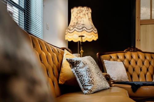 a couch with pillows on it next to a lamp at Huis 7 in Ypres
