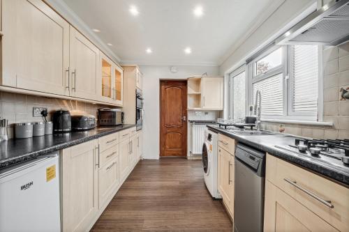 eine große Küche mit weißen Schränken und einem Waschbecken in der Unterkunft Comfortable and Spacious Home - Free Parking in Bedford