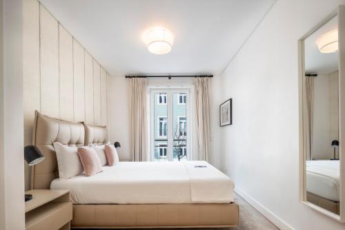 una camera bianca con un grande letto e uno specchio di Marques Best Apartments | Lisbon Best Apartments a Lisbona