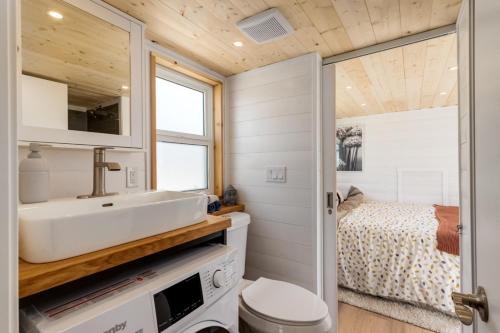 a bathroom with a sink and a toilet and a bed at Mini Muskoka Getaway - Huntsville in Huntsville