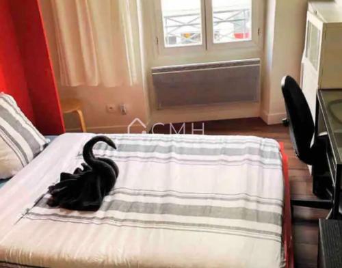 un oiseau noir assis sur un lit avec une couverture dans l'établissement Studio Paisible - En plein coeur de Paris, à Paris