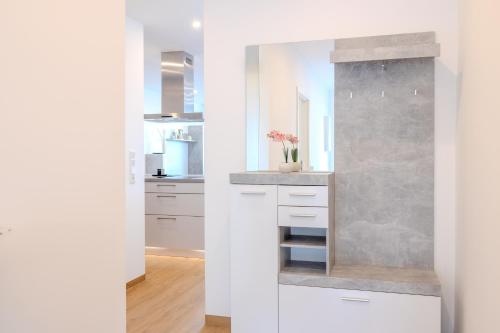 a kitchen with white cabinets and a stone wall at Premium Zuhause - Seeblick, Balkon & Seepromenade in Langscheid