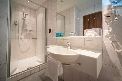 a white bathroom with a sink and a shower at Hotel Alte Post in Feld am See