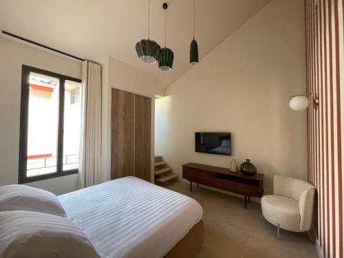 - une chambre avec un lit, une télévision et une chaise dans l'établissement Villa Chiesa, au Grau-du-Roi