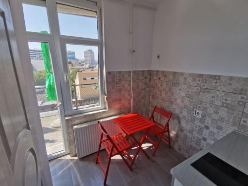 uma mesa vermelha e duas cadeiras num quarto com uma janela em Apartment Modena Novi Sad em Novi Sad