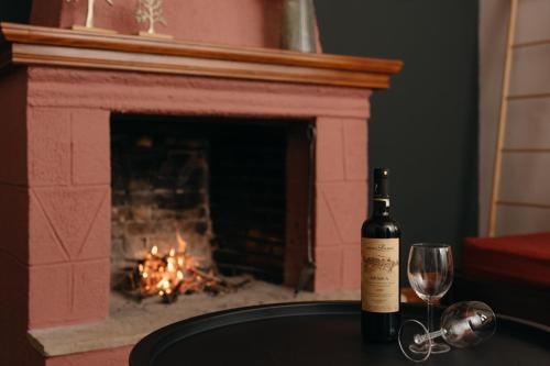 a bottle of wine and a glass on a table with a fireplace at Chrysiida Apartments Kalavrita in Kalavrita