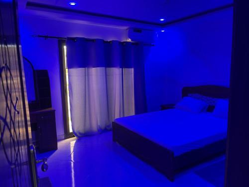 a blue bedroom with a bed and a window at Résidence Cheikh Mahy Cisse Appartements, studios et chambres a louer meublé et climatisé in Kaolack