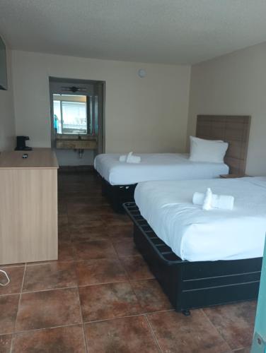 two beds in a room with a counter and a kitchen at Altamonte Springs Hotel and Suites in Orlando
