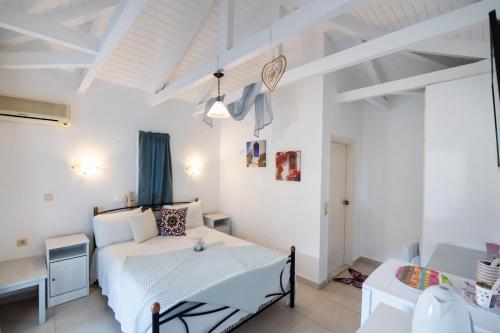 a bedroom with a white bed and a table at Hotel Selini in Agios Nikitas