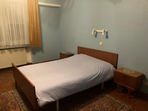 1 Schlafzimmer mit einem Bett mit weißem Bettlaken und 2 Tischen in der Unterkunft Hotel Direndall in Kopstal
