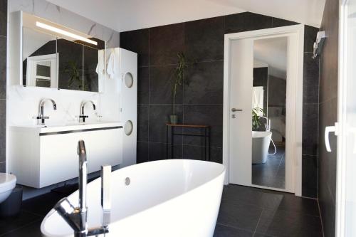 y baño con bañera blanca y lavamanos. en Entire modern villa with outdoor swimming pool!, en Treyvaux