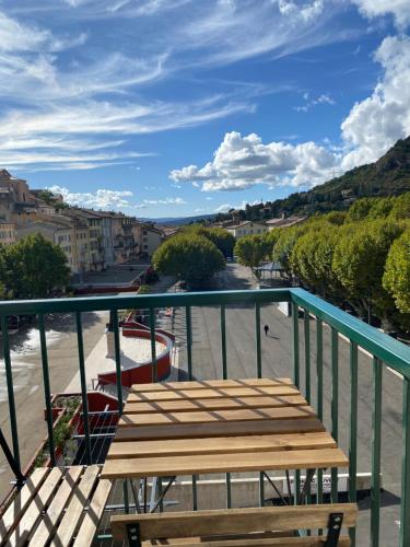 d'un balcon avec une table en bois et une vue sur la rue. dans l'établissement Superbe Studio Centre Digne les bains, à Digne-Les-Bains