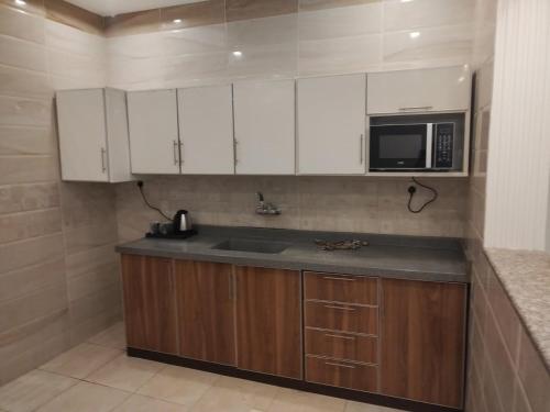 a kitchen with white cabinets and a sink and a microwave at كازا رست للوحدات السكنية in Ḩayy aş Şāliḩīyah