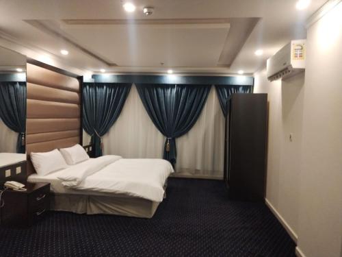 a bedroom with two beds and blue curtains at كازا رست للوحدات السكنية in Ḩayy aş Şāliḩīyah