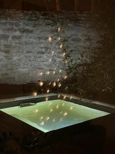 d'une baignoire avec des lumières dans un mur en pierre. dans l'établissement Villa Verde Suite familiale100M2, 2 chambres, terrasse privative Possibilité table d'hôte, à Boisseron