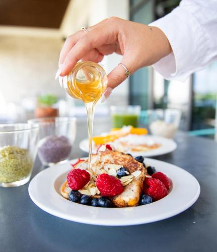 Iemand giet siroop over een bord met eten. bij Hilton Tulum Riviera Maya All-Inclusive Resort in Tulum