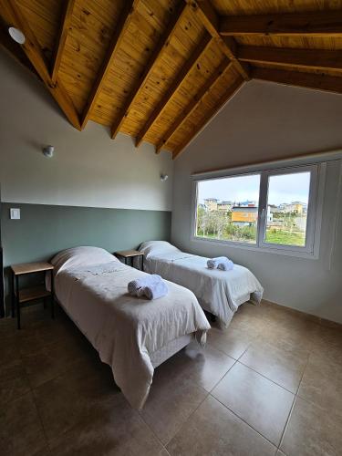 two beds in a room with a large window at Monte Fueguino in Ushuaia