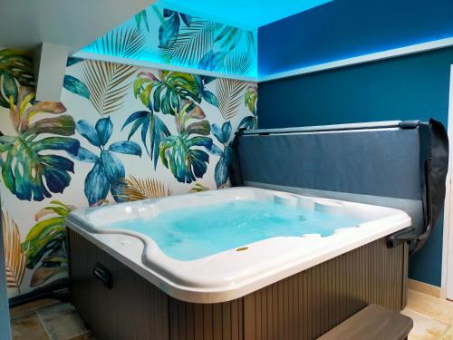 a bath tub in a bathroom with a tropical wallpaper at Cèdre et Charme in Saint-Branchs