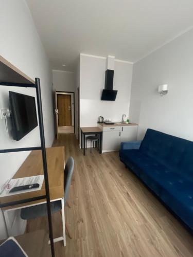 a living room with a blue couch and a desk at Aparthotel Dworzec in Elblag