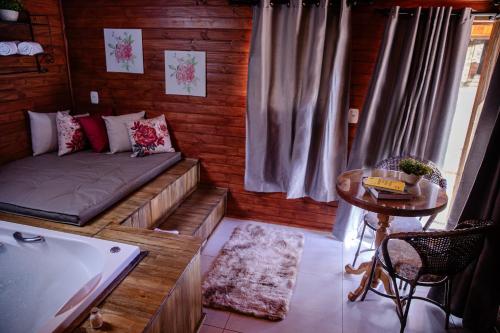 a room with a couch and a table and a tub at Refúgio do Caracol Pipas e Chalés in Canela
