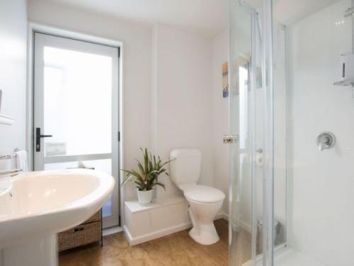 a bathroom with a toilet and a sink and a shower at In the Heart of the Beach in Waihi Beach