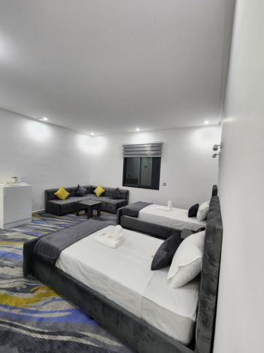 a bedroom with two beds and a flat screen tv at فندق الشموخ Hotel Al Shmokh in Bir Gandouz