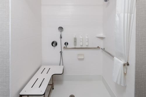 Baño blanco con banco y ducha en Hampton Inn Monticello, Ny, en Monticello