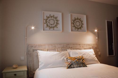 ein Schlafzimmer mit einem weißen Bett mit zwei Bildern an der Wand in der Unterkunft ROTA - Opo airport house in Maia