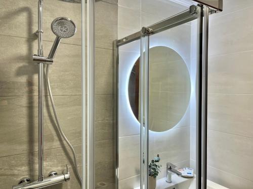 ducha con puerta de cristal y espejo en Nuevo Piso en Couto, en Ourense