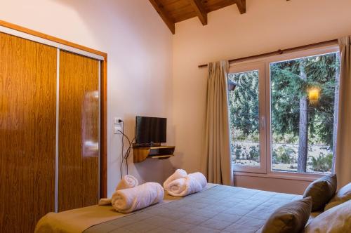 1 dormitorio con 1 cama con toallas en BOG Apart Foresta - A minutos del cerro bayo en Villa La Angostura
