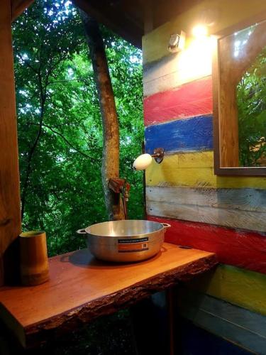 a bowl on a wooden table in front of a window at cabane entre les arbres in Deshaies