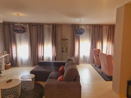 uma sala de estar com um sofá, cadeiras e janelas em Casa Rural La Botica em Jarandilla de la Vera