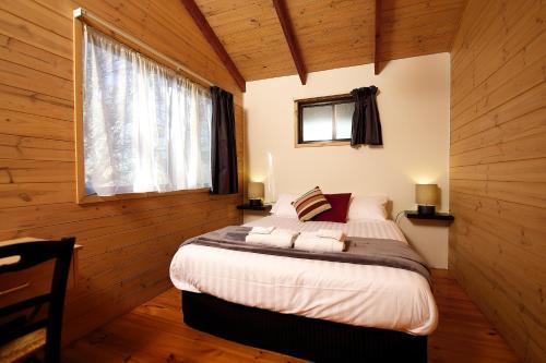 ein Schlafzimmer mit einem Bett in einem Zimmer mit Holzwänden in der Unterkunft Lakes and Craters Holiday Park in Camperdown