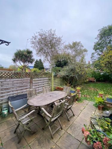 a wooden table and chairs in a garden at Charming & Spacious 2BD House wGarden - Wimbledon in Raynes Park