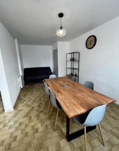La Haye-du-Puits的住宿－MAISON DE VILLE，餐桌、椅子和墙上的时钟