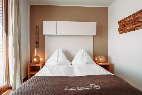 Schlafzimmer mit einem Bett mit weißer Bettwäsche und Kissen in der Unterkunft WeinHAUS 03 im Weingarten-Resort Unterlamm Loipersdorf - ADULTS ONLY in Unterlamm