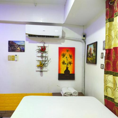 a room with a bed and paintings on the wall at Cozy Condo Unit w/ FREE WIFI&Netflix-Pay Parking in Antipolo