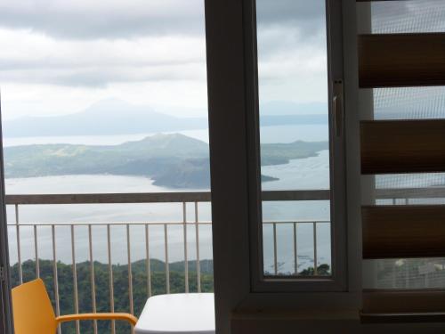 een balkon met uitzicht op het water bij Blowing in the Wind - Lake View Apartments in Tagaytay